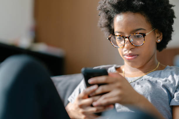 istock Young woman sitting on sofa and using smart phone 1199040648