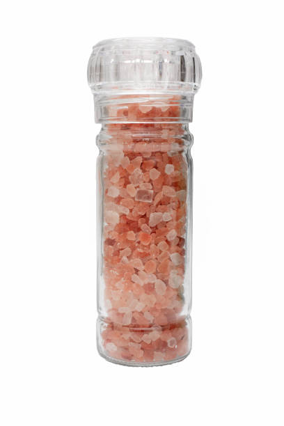 Close up of  Pink Himalayan crystal salt in glass grinder bottle isolated on white background
