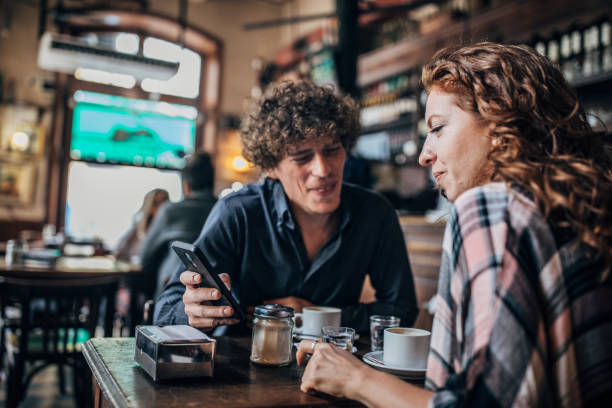 istock Friends using mobile in coffee shop 1199042078