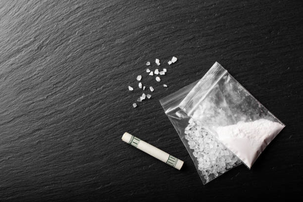 drug powder in a plastic bag on a black background. illegal drug trafficking. stock photo