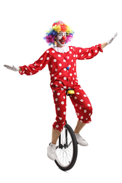 istock Clown in a red polka dot costume riding a unicycle 1199043617