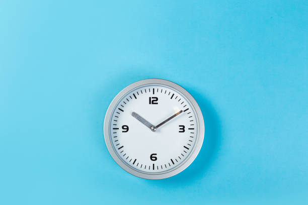 istock minimalistic white wall clock with light metal on a blue background. time concept. 1199046659