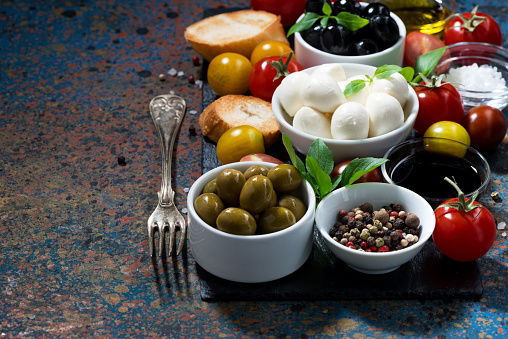 mozzarella, ingredients for the salad and bread on dark background, closeup, horizontal