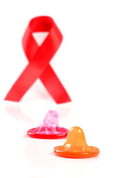 Aids ribbon and condom on white background.