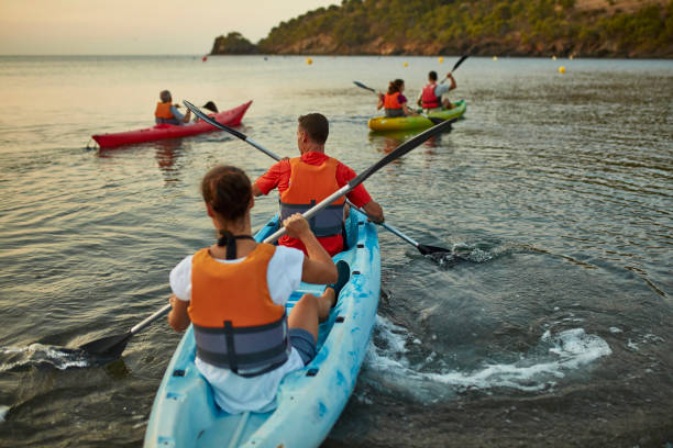 タンデム・カヤッカーズが夜明けにコスタ・ブラバを離れてパドリング - kayaking kayak sea coastline ストックフォトと画像