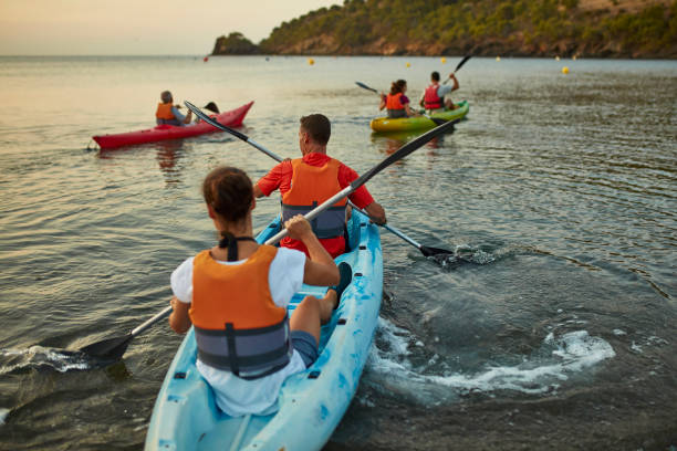 Spanish male and female kayakers in 30s and 40s beginning early morning paddling excursion in Mediterranean Sea off the Costa Brava.