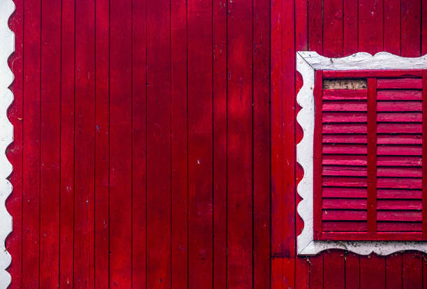 Red wooden wall and windows blind with white decoration frame. Photo taken on 12th of January 2020 in Buzias town, Timis county, Romania.