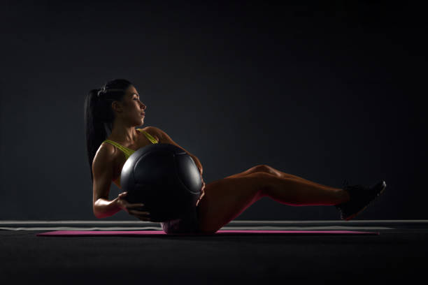 istock Sportswoman training abs with ball in gym. 1199057844