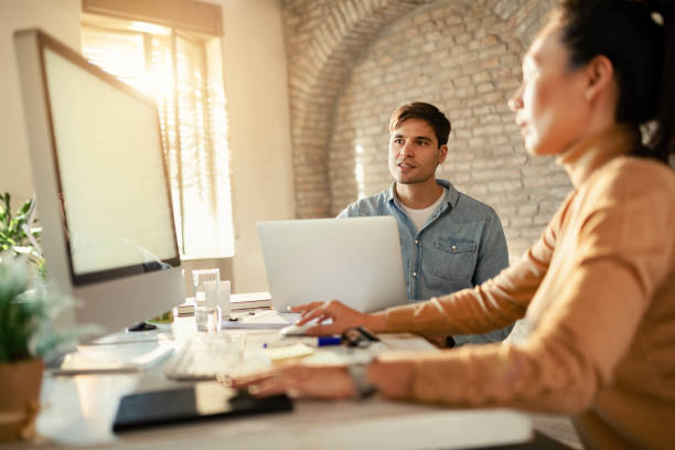 istock Young businessman using laptop while working with female colleague in the office. 1199057998