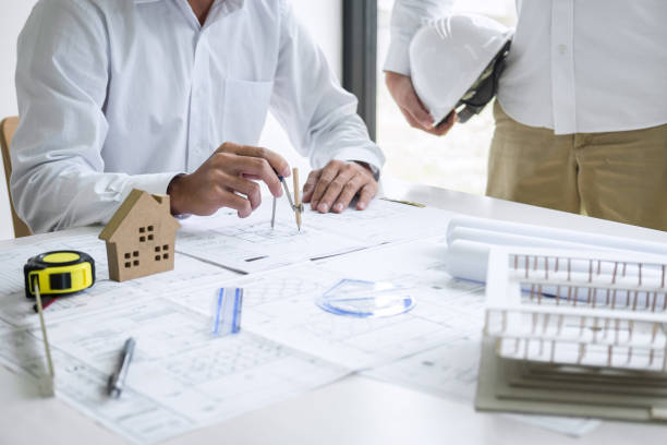 istock Team of engineering or architect meeting and discussing on blueprint and building model while checking information on sketching for architectural project 1199059611