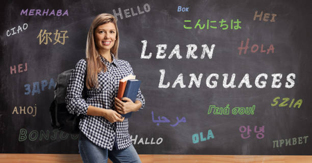 istock Female student with books posing in front of a blackboard with text learn languages 1199060670
