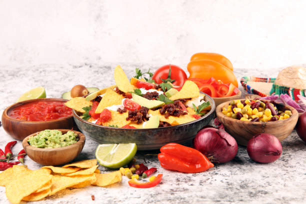 istock mexican nacho chips garnished with ground beef, guacamole, melted cheese, peppers and cilantro leaves in plate 1199060998