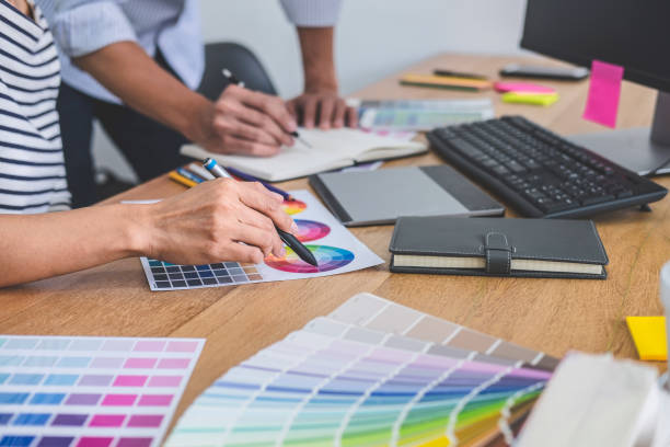 istock Two colleagues creative graphic designer working on color selection and drawing on graphics tablet at workplace, Color swatch samples chart for selection coloring 1199062556