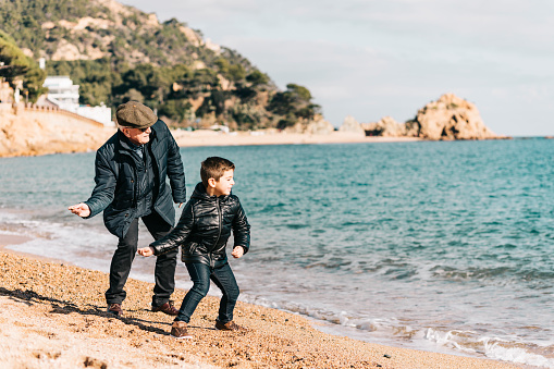 Grandfather and grandson throwing rocks on the beach