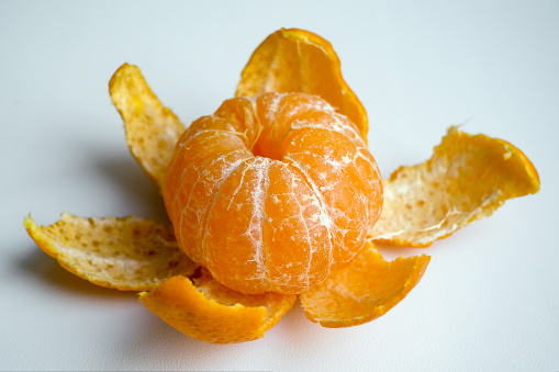 Peeled tangerine or mandarin fruit on white background, flower from mandarin