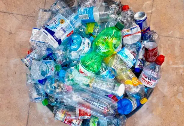 Overfilled trash can with crushed colorful plastic bottles waiting for recycle