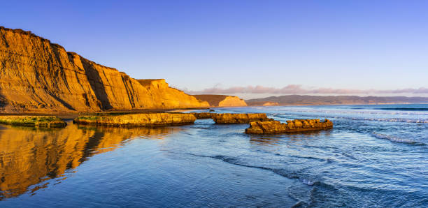 太平洋の海岸線の夕日の眺め、濡れた砂に映る黄金色の崖、ドレイクスビーチ、ポイントレイエス国立海岸、カリフォルニア州 - point reyes national seashore northern california beach california ストックフォトと画像