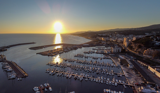 Dramatic sunset over the mediterranean sea in El Maresme Coast. Aerial panoramic view of Arenys de Munt harbor at dawn.