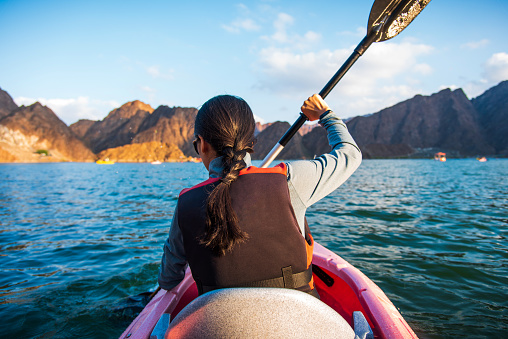 Woman kayaking in a scenic lake surrounded by mountains , active lifestyle