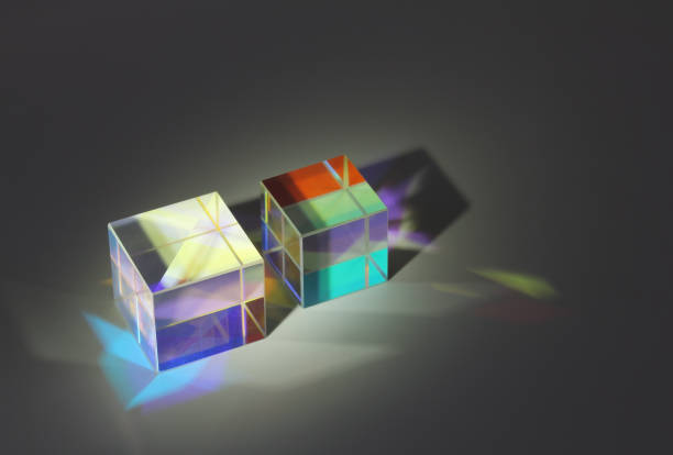 Two cube glass prism refract light into different colors and cast shadows Two cube glass prism on the surface refract light into different colors and cast shadows. On a dark background close-up facet joint photos stock pictures, royalty-free photos & images
