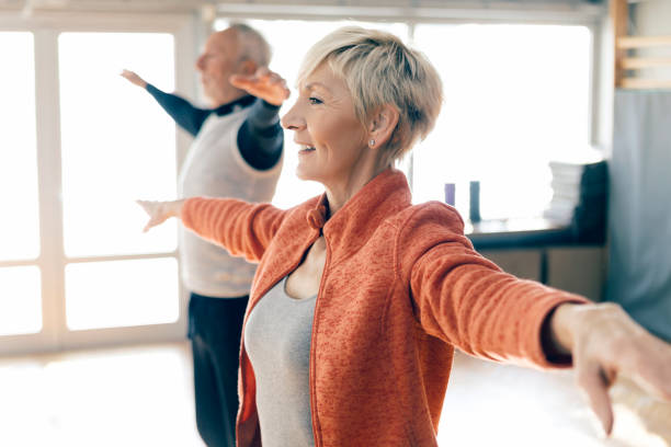 anziani attivi in classe fitness che allungano le braccia - posizione corretta foto e immagini stock