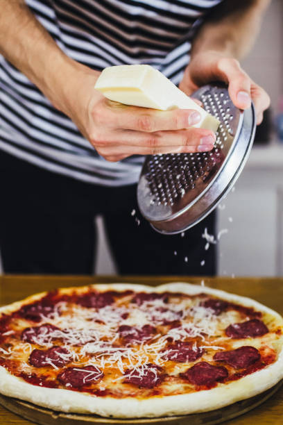 istock Chef rubbing grana padano cheese over raw pizza dough 1199085215