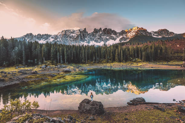 junge frau genießt in der natur auf dem felsen am lago di carezza, dolomiten, italien - latemar mountain range stock-fotos und bilder