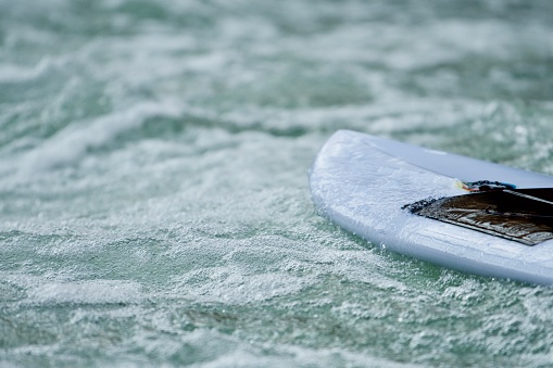 A white surfboard on foamy white waters