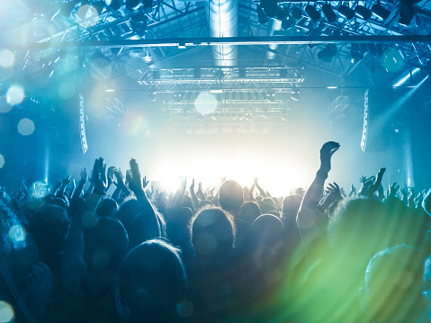 Concert spectators in front of a bright stage with live music