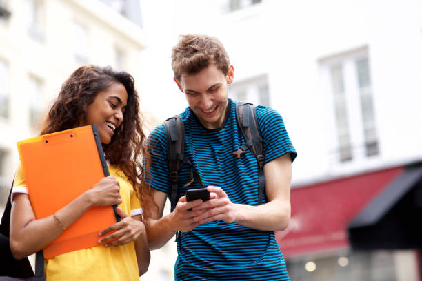 istock happy college students laughing and looking at mobile phone 1199097291
