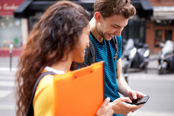 istock happy students looking at mobile phone in city 1199097294