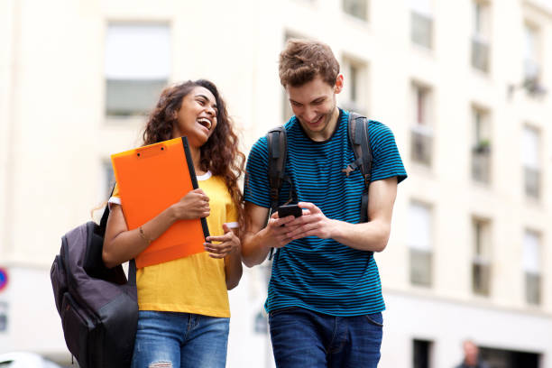istock happy students walking with bag and mobile phone 1199097296