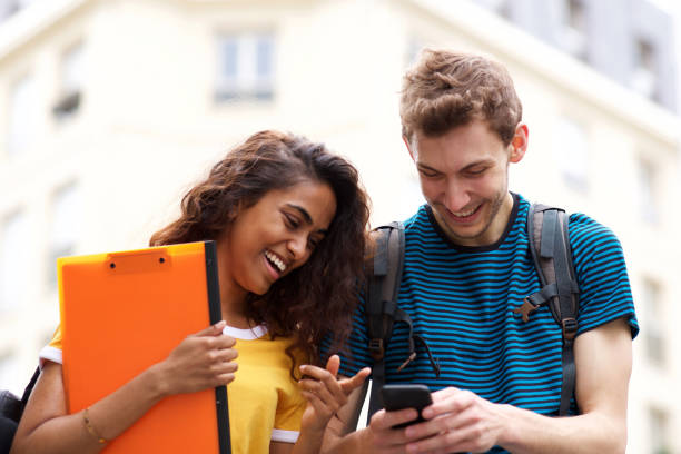 istock smiling college students looking at mobile phone while in city 1199097329