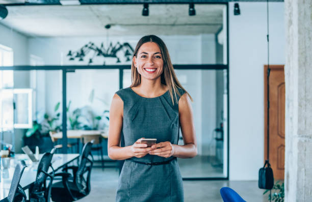 istock Happy businesswoman using phone in modern office. 1199100504