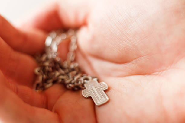 istock Silver cross in the hand with focus on the cross, shallow DOF 1199103049