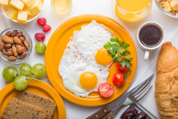 Homemade breakfast with sunny side up fried egg toast coffee fruits vegetable and orange juice in top view with copy space. Delicious homemade american breakfast concept for background. American breakfast on breakfast table.