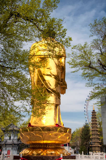 A gold standing buddha statue on a sunny blue sky spring day at Jile Temple in Harbin China.