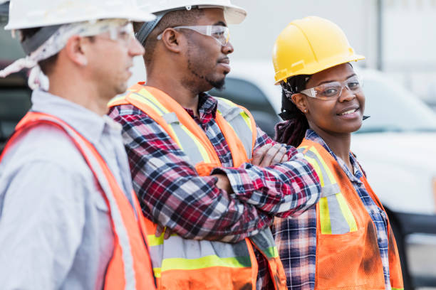 drei bauarbeiter in hardhats und sicherheitswesten - horizontal female with group of males posing looking at camera stock-fotos und bilder