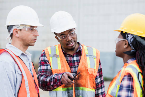 istock Three construction workers in hardhats and safety vests 1199107492