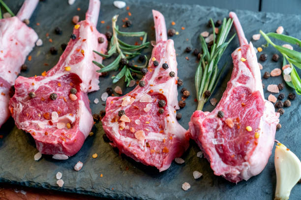 istock Raw Lamb Chops Prepared on a Dark Slate Cutting Board with a Ramekin or Pesto on the side with Rosemary and other herbs 1199113699