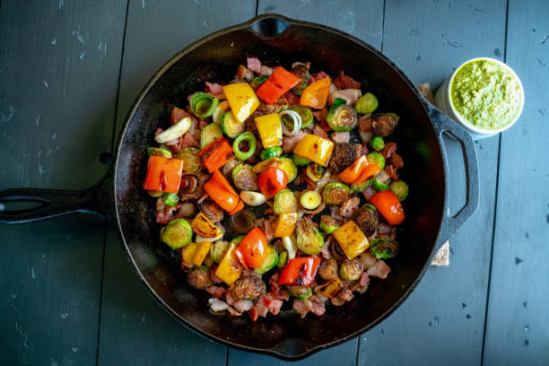 medley vegetal do estilo mediterrâneo em uma frigideira do ferro de molde que inclui sprouts de bruxelas, pimenta de sino, cebola, bacon - roasted vegetable food pepper - fotografias e filmes do acervo