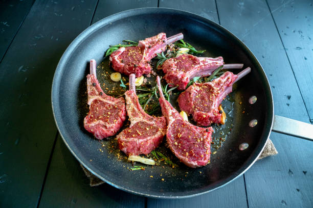 Raw Lamb chops in a Skillet Ready to be cooked with garlic, leeks, and rosemary as seasoning Raw Lamb chops in a Skillet Ready to be cooked with garlic, leeks, and rosemary as seasoning mutton stock pictures, royalty-free photos & images