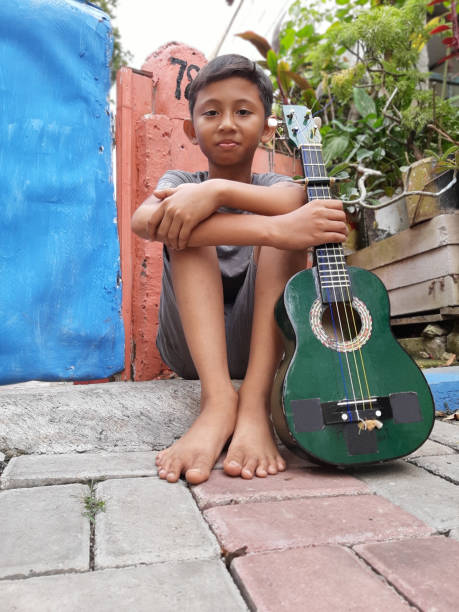 A Young Indonesian Boy Plays His Mandolin.