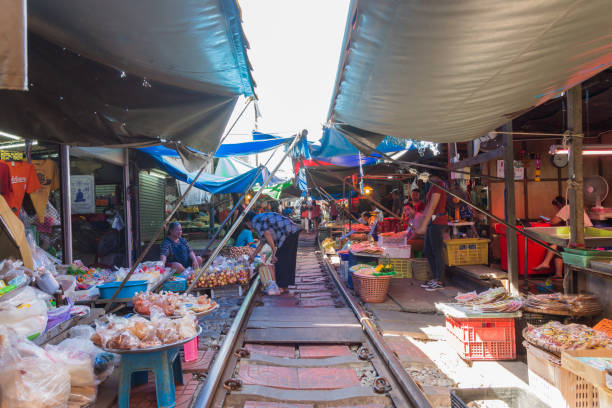 Tourists can seen exploring and shopping along the Maeklong Railway Market.It is a Thai market selling fresh vegetables,food, fruit,as well as souvenirs and clothing. stock photo