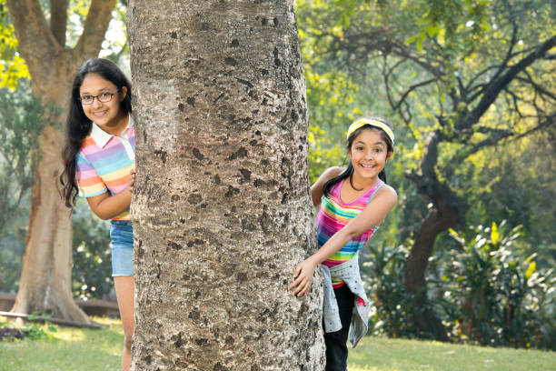 a group of small children in colorful clothes embracing sitting on the grass under a tree in a park laughing and smiling. June 1, Children's Day, vacation, friendship, friends, childhood.