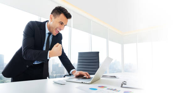 businessman is standing and looking at laptop.