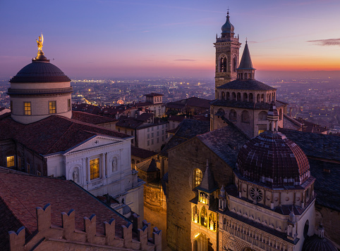 Bergamo, Italy. The old town. Amazing aerial view of the Basilica of Santa Maria Maggiore and the dome of the cathedral during a wonderful sunset. In the background the Po plain