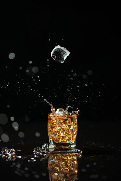 istock One shot of whiskey with splash on black background with reflection 1199148505