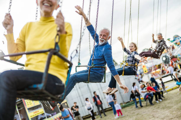 istock Happy seniors having fun while riding on chain swing at amusement park. 1199152990