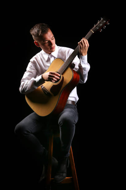 istock Young men playing the guitar with black background 1199156639